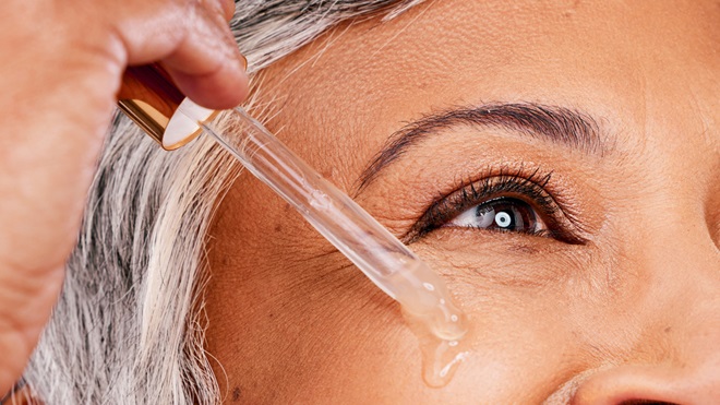 femme agee qui s'applique du serum au retinol sur le visage