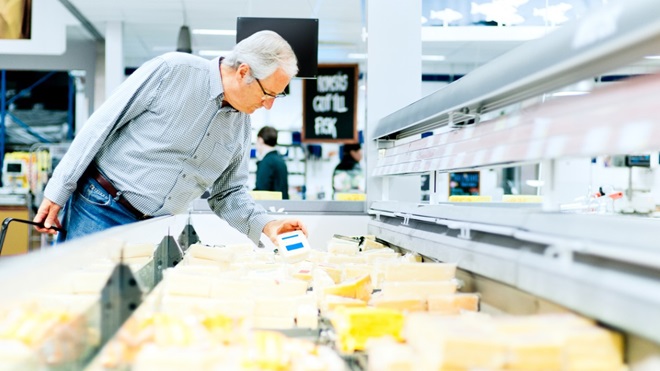 un homme choisit du fromage au supermarché