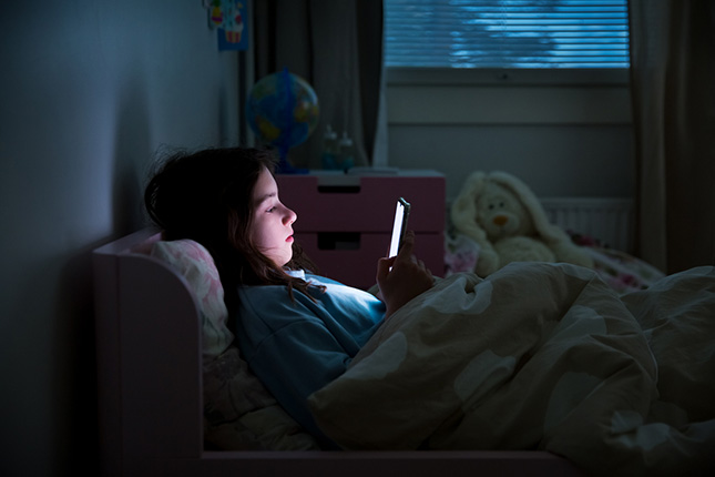 Une ado qui utilise son smartphone dans son nuit