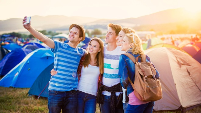 Un groupe d'amis se prend en selfie avec un smartphone au camping d'un festival de musique