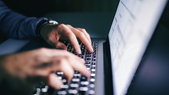 Des doigts pianotent sur le clavier d'un ordinateur.