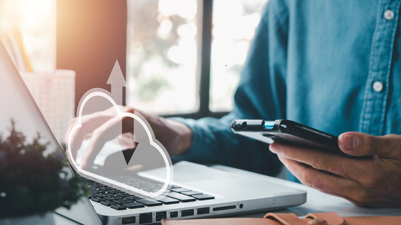 Un homme utilise le stockage en ligne entre son ordinateur et son téléphone.