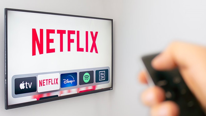 écran télévision netflix main tenant une télécommande