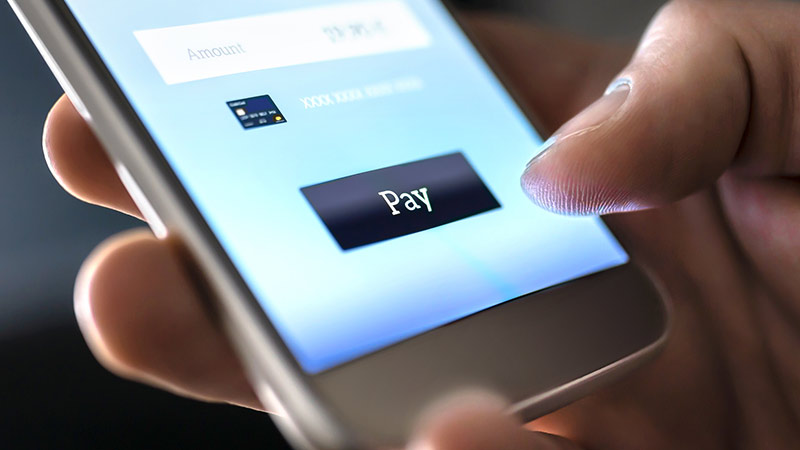 main tenant un smartphone et qui hésite à appuyer sur payer