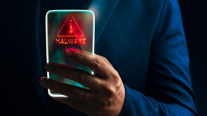 un homme tenant un smartphone sur lequel est écrit malware
