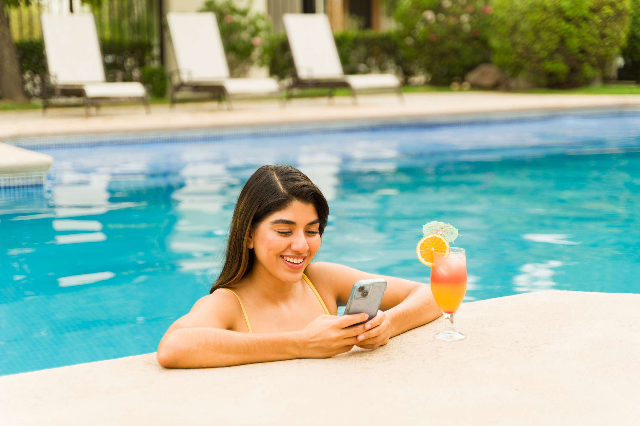 jeune femme en vacances au Mexique et utilisant son smartphone pour surfer sur internet depuis une piscine