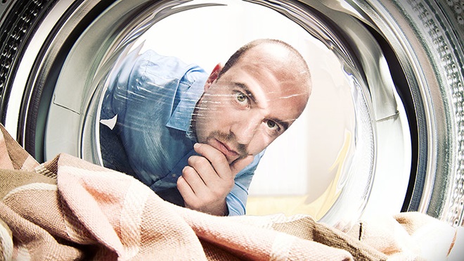 Une femme se tient devant une machine à laver avec du linge qui sent mauvais.