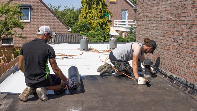 Des ouvriers en train de poser une membrane pour du cool roofing