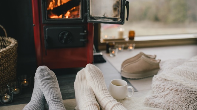 Couple qui se réchauffe devant le poêle à bois en hiver.