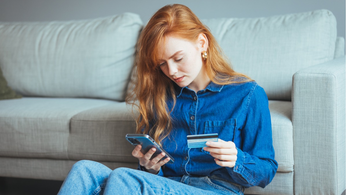 jeune fille avec une carte bancaire qui consulte son smartphone