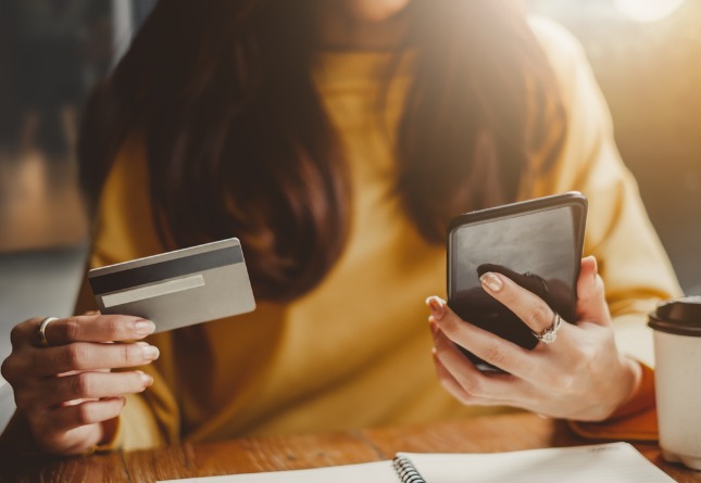 Une femme effectue un achat en ligne avec son smartphone et sa carte de crédit