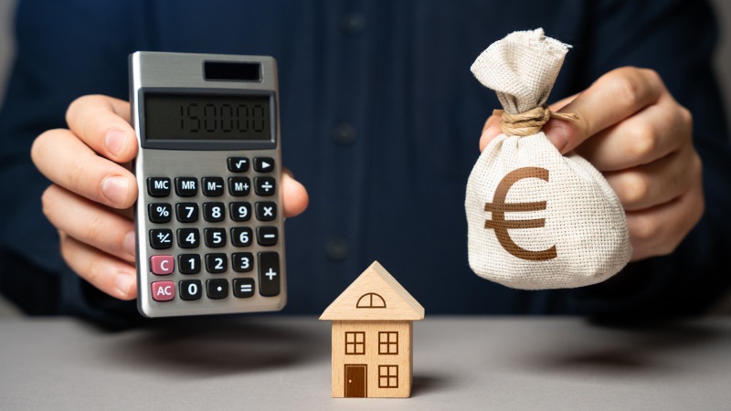 herziening hypothecaire lening, man toont rekenmachine, huis en geld om aan te tonen waarop je moet letten