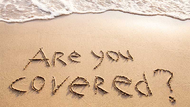 Mention "are you covered?" dessinée sur le sable
