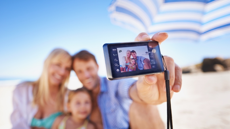Une famille fait un selfie avec un appareil photo numérique.