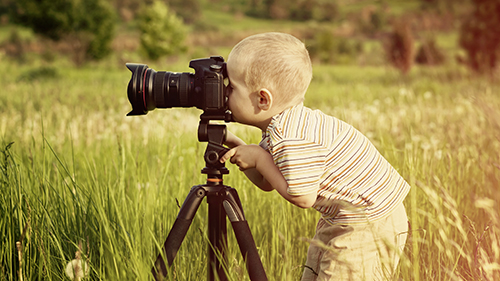 Un jeune enfant regarde dans le viseur d'un appareil photo.