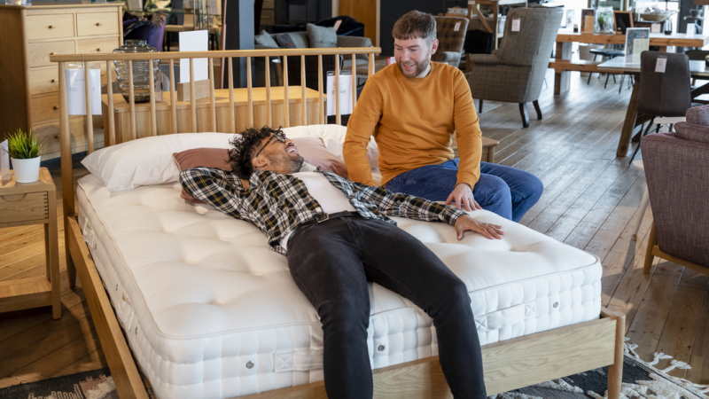 Deux hommes testent un matelas dans un magasin.